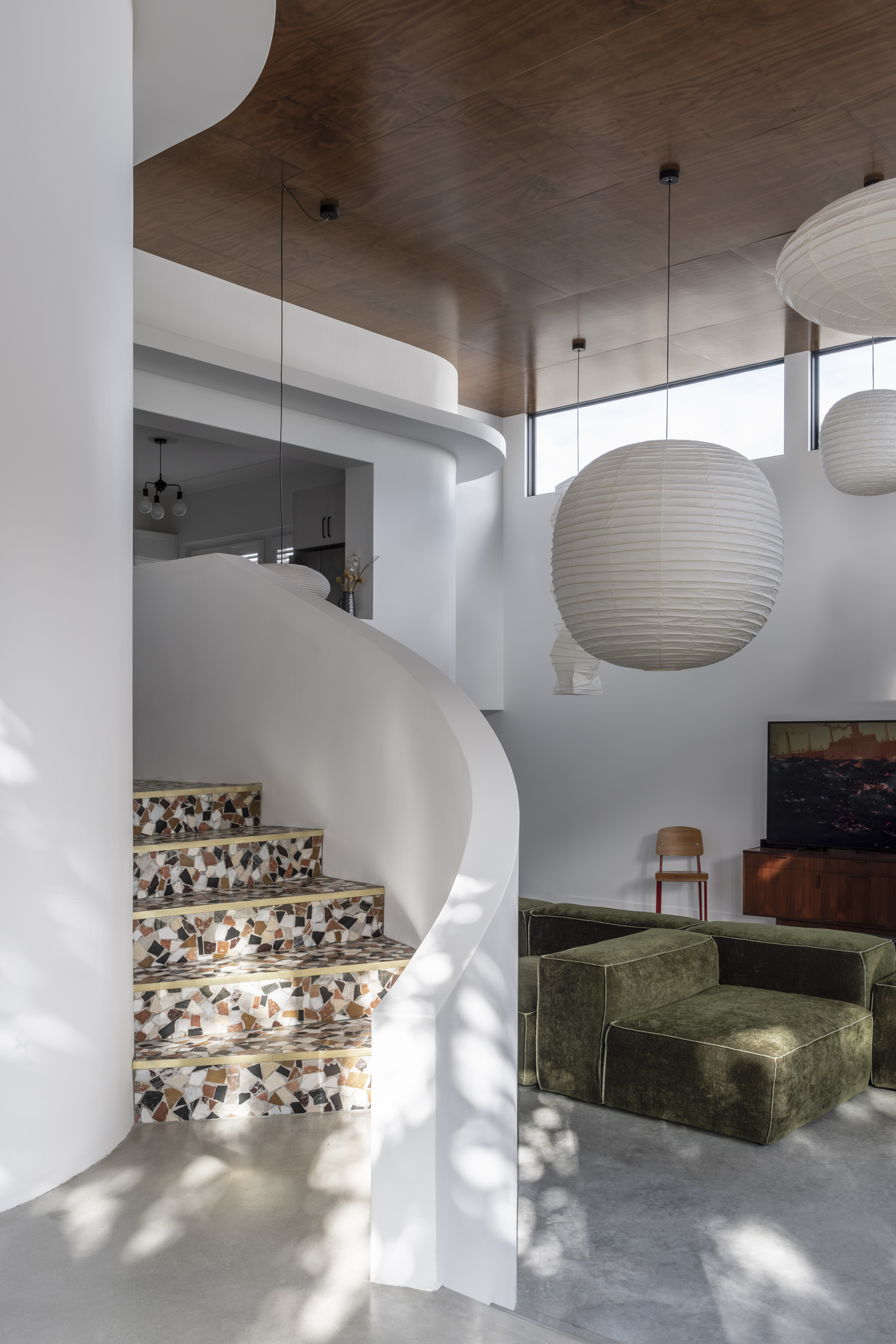 Interior — curved white staircase with terrazzo steps, pendant lights and green sofa