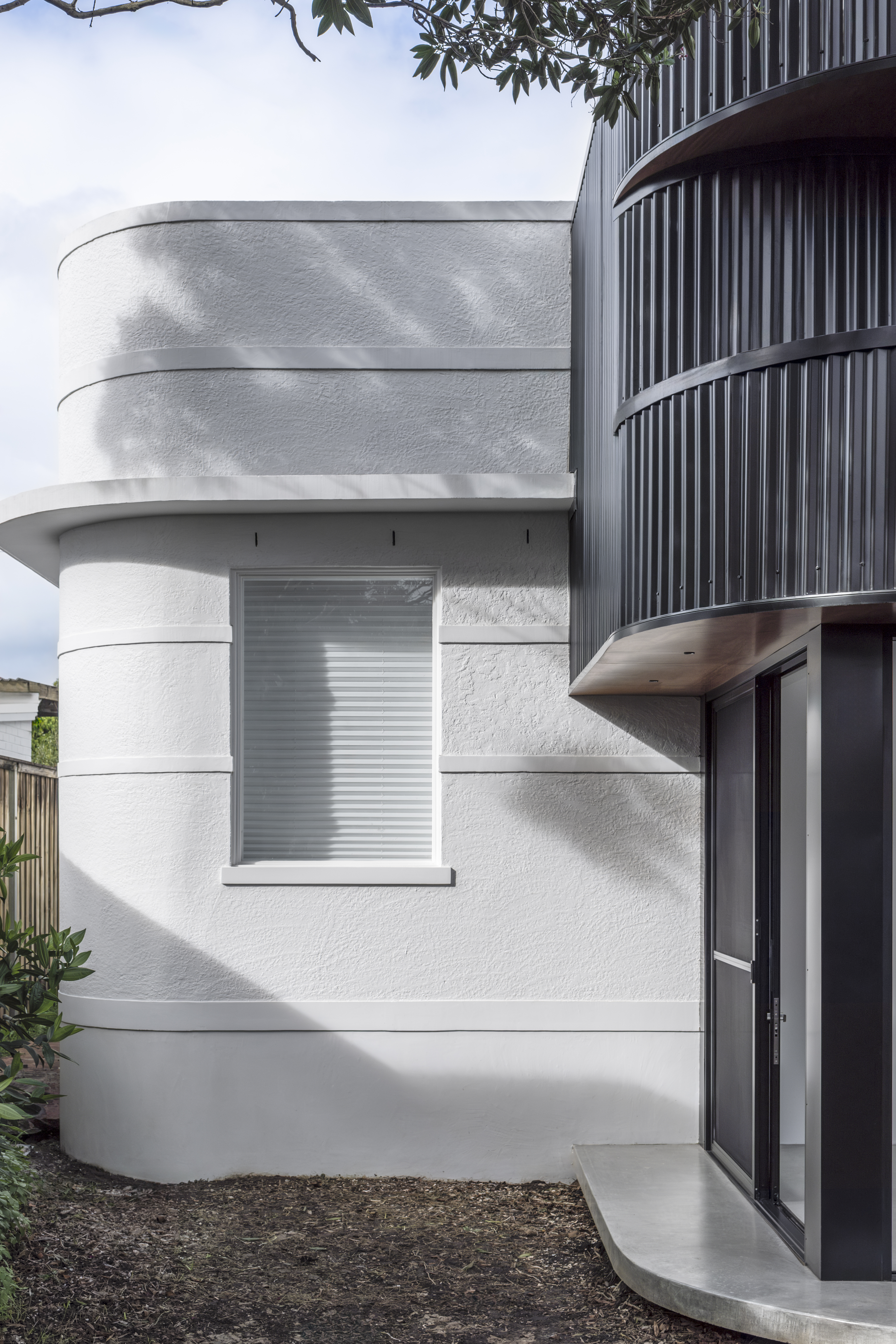 Exterior — white rendered curved walls with window and black cladding tower above