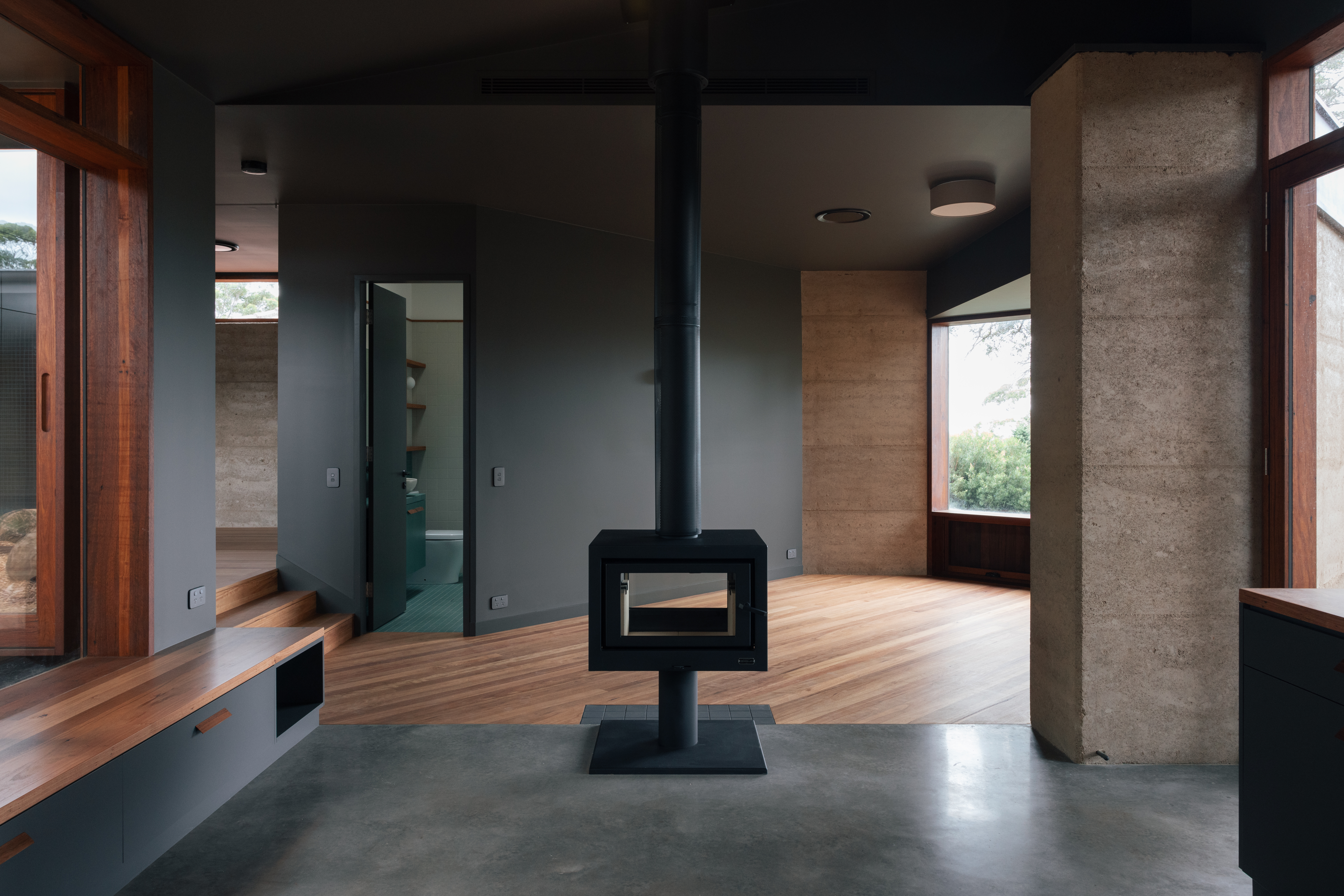Exterior — hardwood deck with rammed earth and dark metal cladding