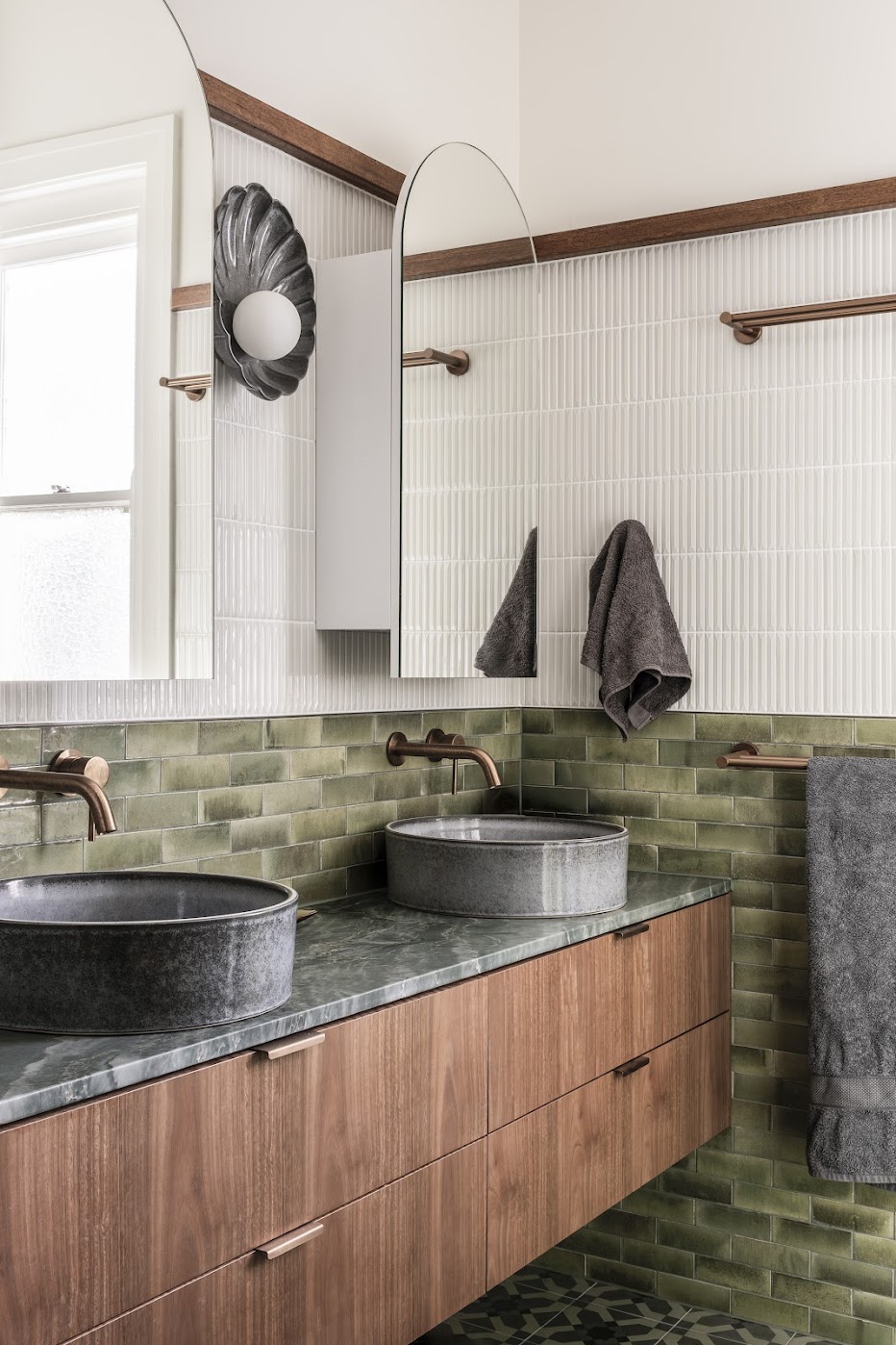 Bathroom — green glazed subway tiles, walnut floating vanity, vessel basins, copper tapware and arch mirror